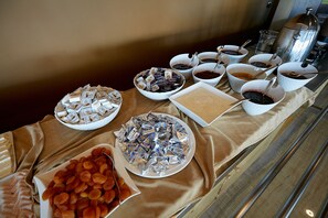 A buffet table with various food items and condiments. - ETER Hotel (Golem)