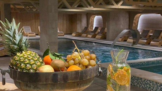 A metal bowl filled with fruits and a glass pitcher with a lemon slice. - ETER Hotel (Golem)