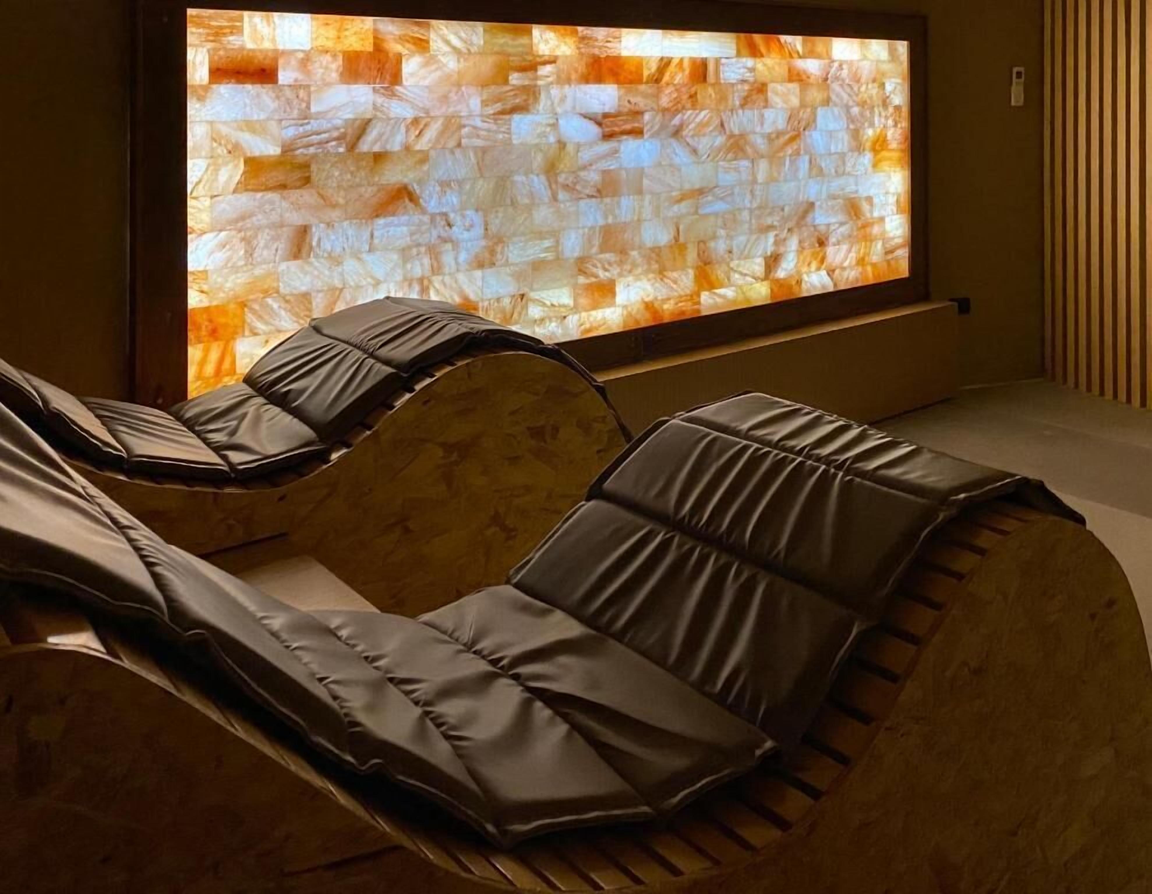 A massage therapy room with two massage chairs and a large wall-mounted screen displaying a textured pattern.