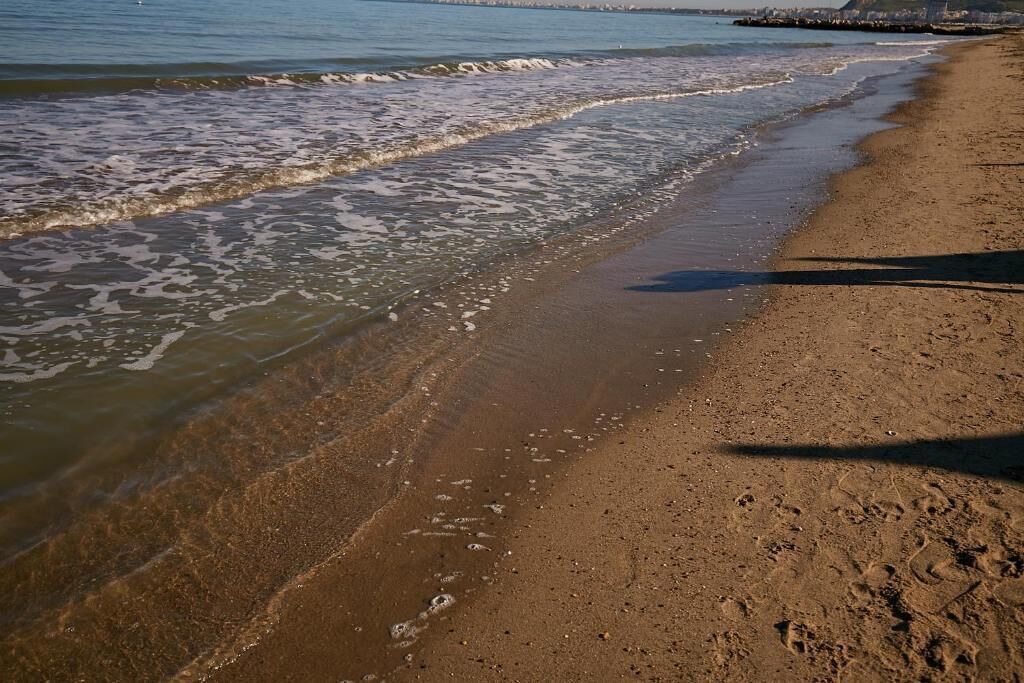 A sandy beach with gentle waves lapping at the shore.