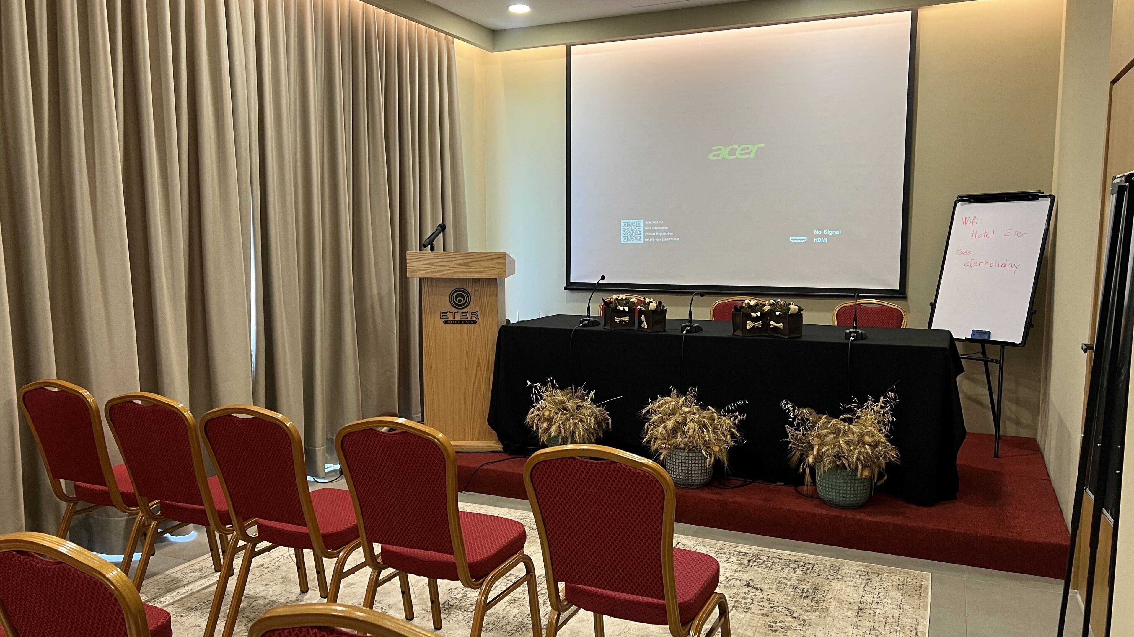 A conference room with a podium, a whiteboard, and a screen displaying 'acer' and 'HDMI'.