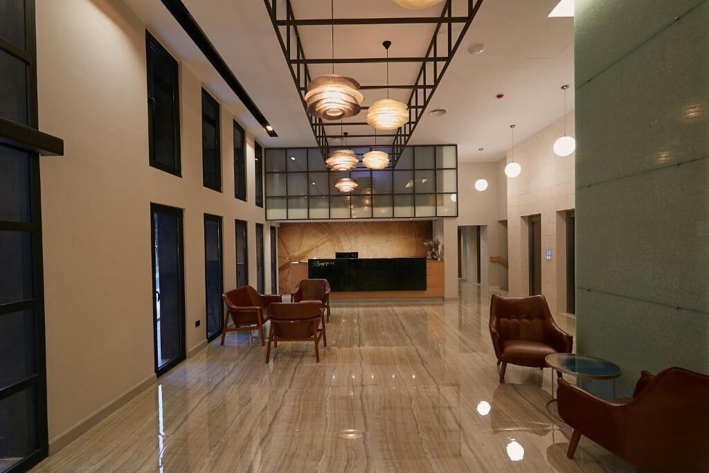 A spacious lobby with a reception desk, seating area, and large windows.