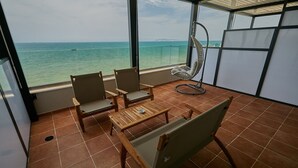 A balcony with a view of the sea, two wooden chairs, a small table, and a hanging chair. - ETER Hotel (Golem)