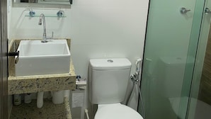 A bathroom with a sink, toilet, and glass shower enclosure.