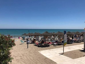 A beachside hotel with thatched-roof structures, sun loungers, and a clear view of the sea. - Rentcostadelsol Doña Sofia 3D (Fuengirola)