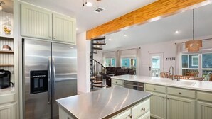 Eine moderne Küche mit Edelstahlgeräten, hellgrünen Schränken und einem Holzbalken an der Decke.