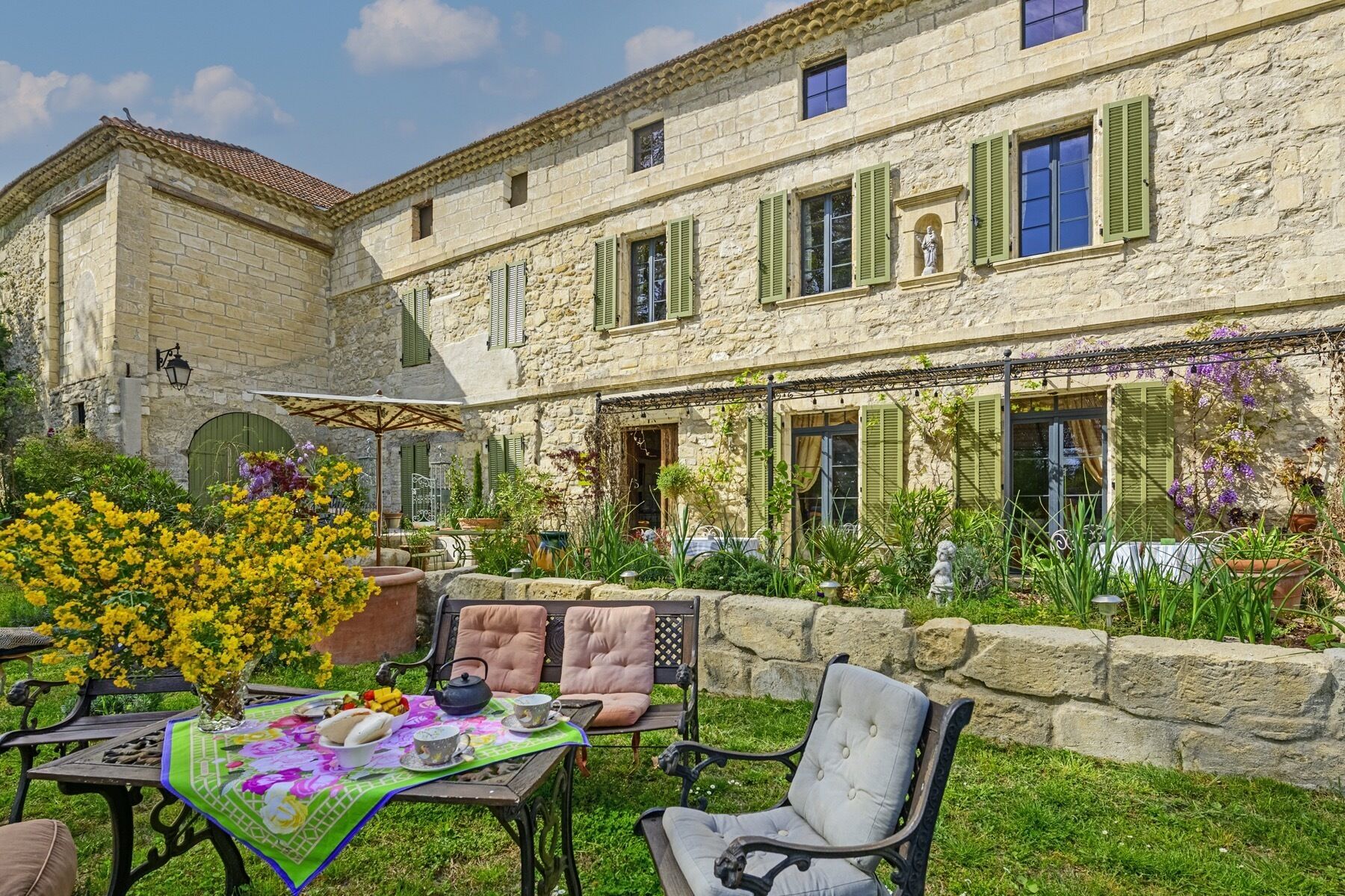 A stone building with a courtyard, outdoor seating, and a variety of plants.