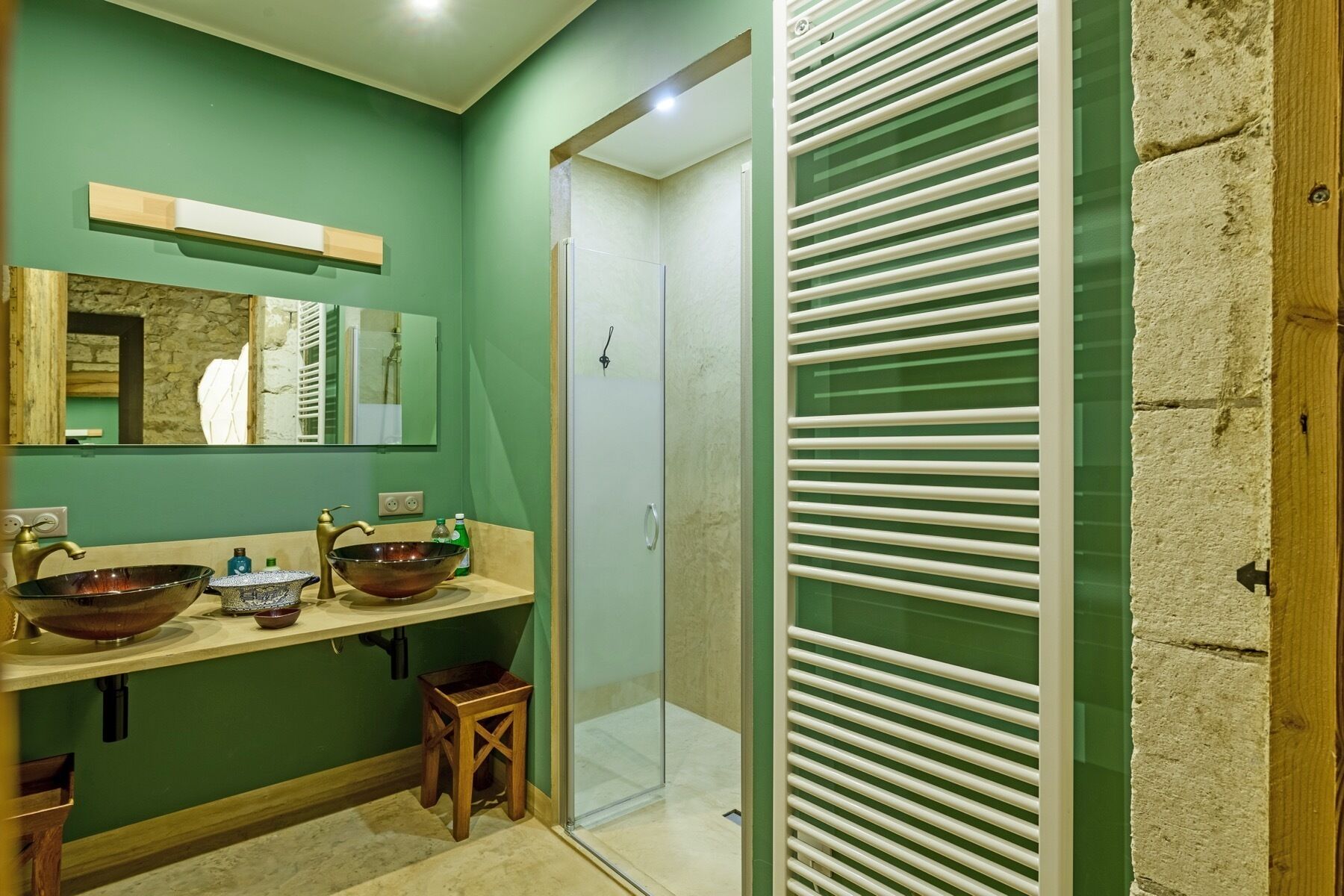 A bathroom with two sinks, a mirror, a shower, and a glass door.