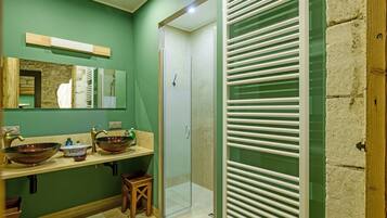 A bathroom with two sinks, a mirror, a shower, and a glass door.