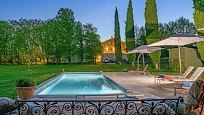 A swimming pool with a patio area, lounge chairs, and an umbrella. - Bastide de Bellegarde (Avignon)