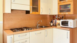 Una cucina con mobili in legno, un piano cottura a gas, un lavello e un forno a microonde.