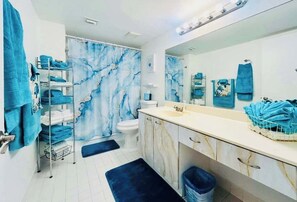 Bathroom features a toilet, sink, and mirror, along with a towel rack and trash bin.