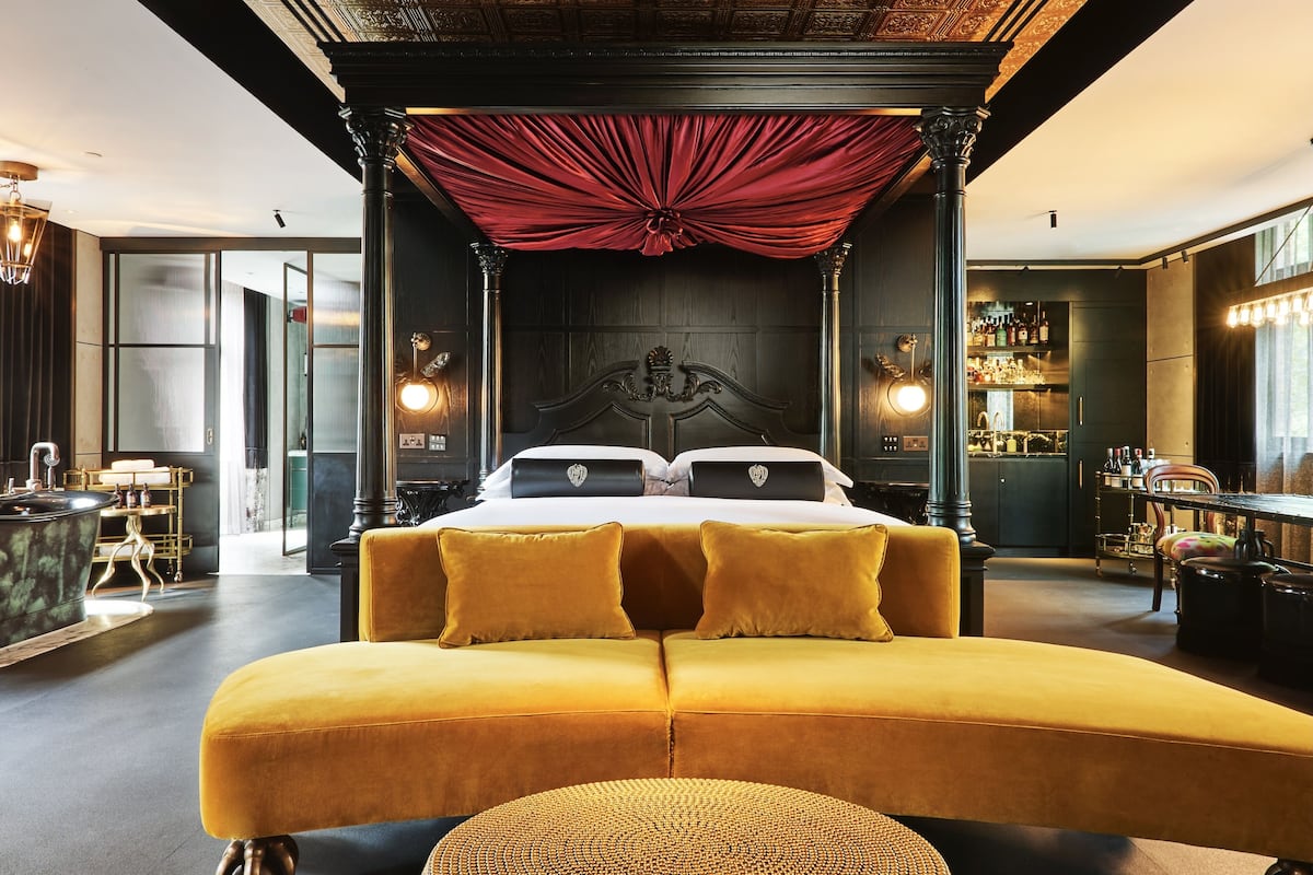 A luxurious room with a large bed, a bar area, and a seating area.