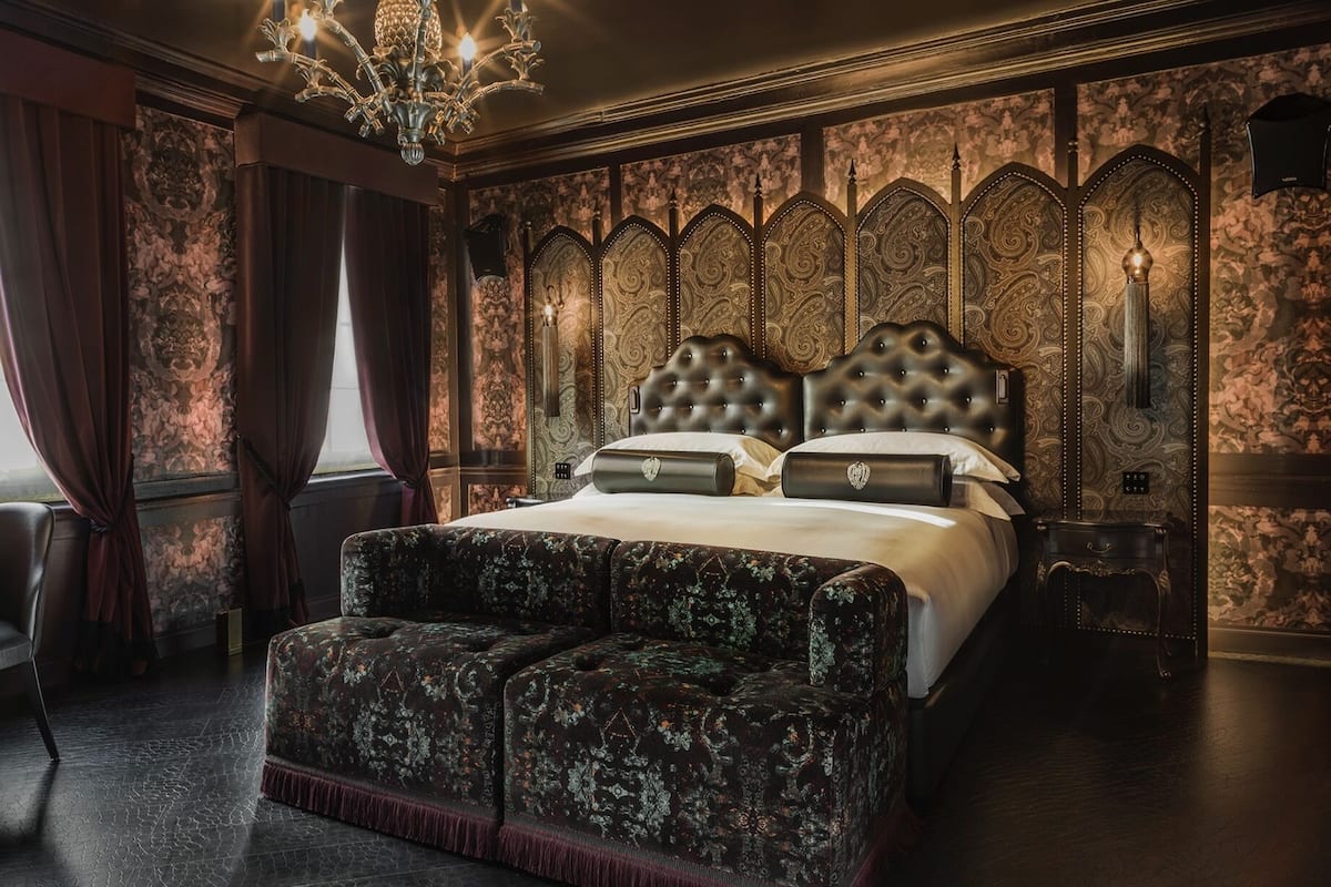 A luxurious bedroom with a large bed, ornate headboard, and a chandelier.