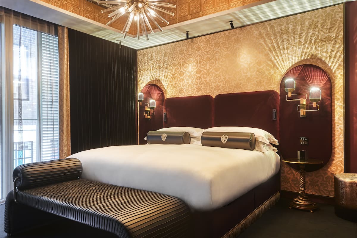 A hotel room with a large bed, a bedside table, and a decorative wall.