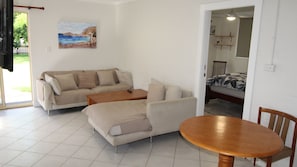 A living room with a sofa, a coffee table, and a bed with a patterned bedspread.