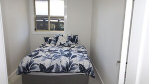A bedroom with a bed, a window, and a door.