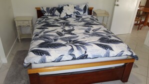 Ein Bett mit floralem Überwurf, zwei Nachttische und ein hölzernes Kopfteil.