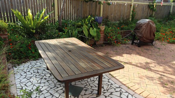 A patio with a wooden table and a mosaic floor.