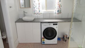 Ein kleines Badezimmer mit Waschmaschine, Waschbecken und Toilette.