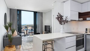 A modern kitchen with a central island, built-in appliances, and a view to the outdoors. - Lush Sky Apartment With Ocean Views (Cape Town)