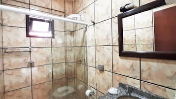 A bathroom with a marble-tiled shower enclosure, a hand dryer, a towel rack, and a mirror.
