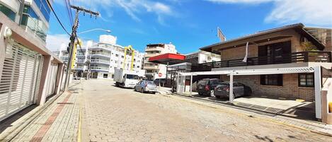 A street with buildings, a sidewalk, and parked cars.