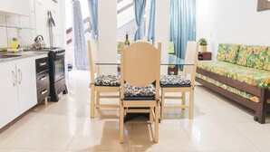A modern kitchen with white cabinets, a gas stove, and a dining area with two chairs and a table. - Agua Marinha de Bombas - Bombinhas (Bombinhas)