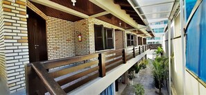 Enjoy the tranquil atmosphere on this multi-level balcony with a brick wall and wooden railings, surrounded by lush potted plants.