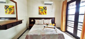 Relax in this serene space with a large bed, bedside table, and air conditioning units for a comfortable stay.