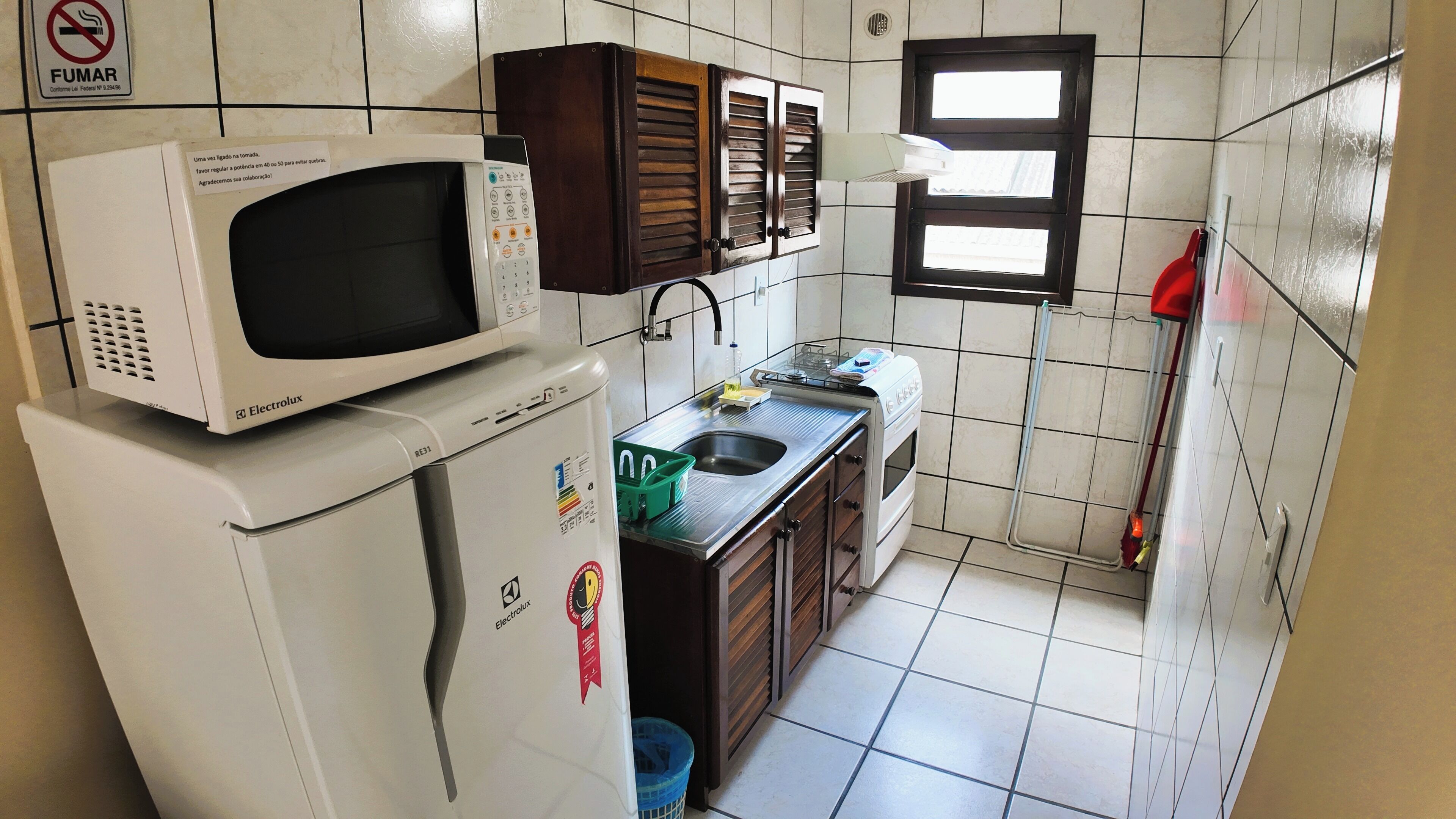 A compact kitchen with a microwave on a refrigerator, a sink, and wooden cabinets.