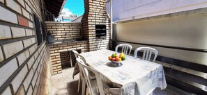 Enjoy casual dining in this outdoor space with a brick oven, table, and comfortable seating.