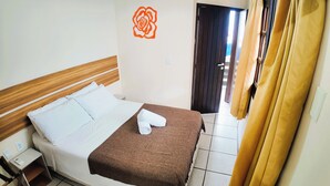 A hotel room with a wooden headboard, white bedding, a brown throw blanket, and a wall decoration of a rose. - Agua Marinha de Bombas - Bombinhas (Bombinhas)