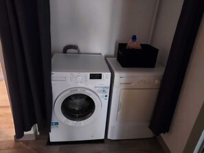 Un área de lavandería compacta con lavadora de carga frontal y secadora apilada.