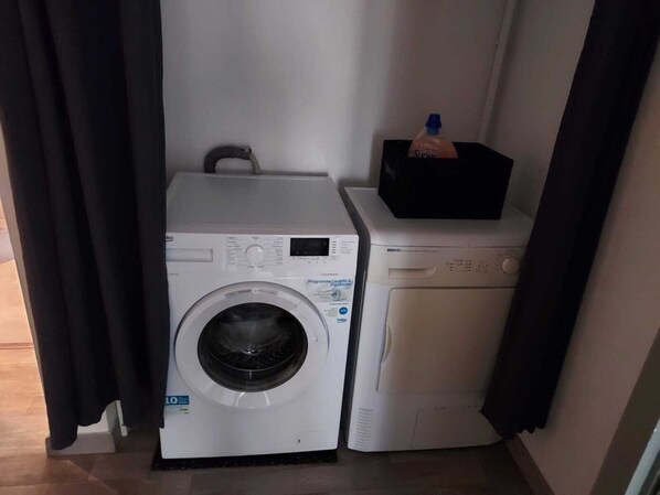 A compact laundry area with a front-loading washing machine and a stacked dryer.