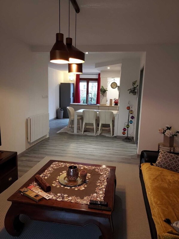 A living room with a coffee table, a sofa, and a dining area with chairs and a table.