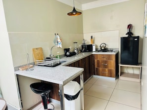 A compact kitchen with a sink, stove, microwave, and a black refrigerator.
