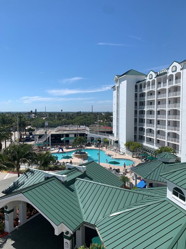 A resort with a large pool area, multiple balconies, and a view of the surrounding landscape.