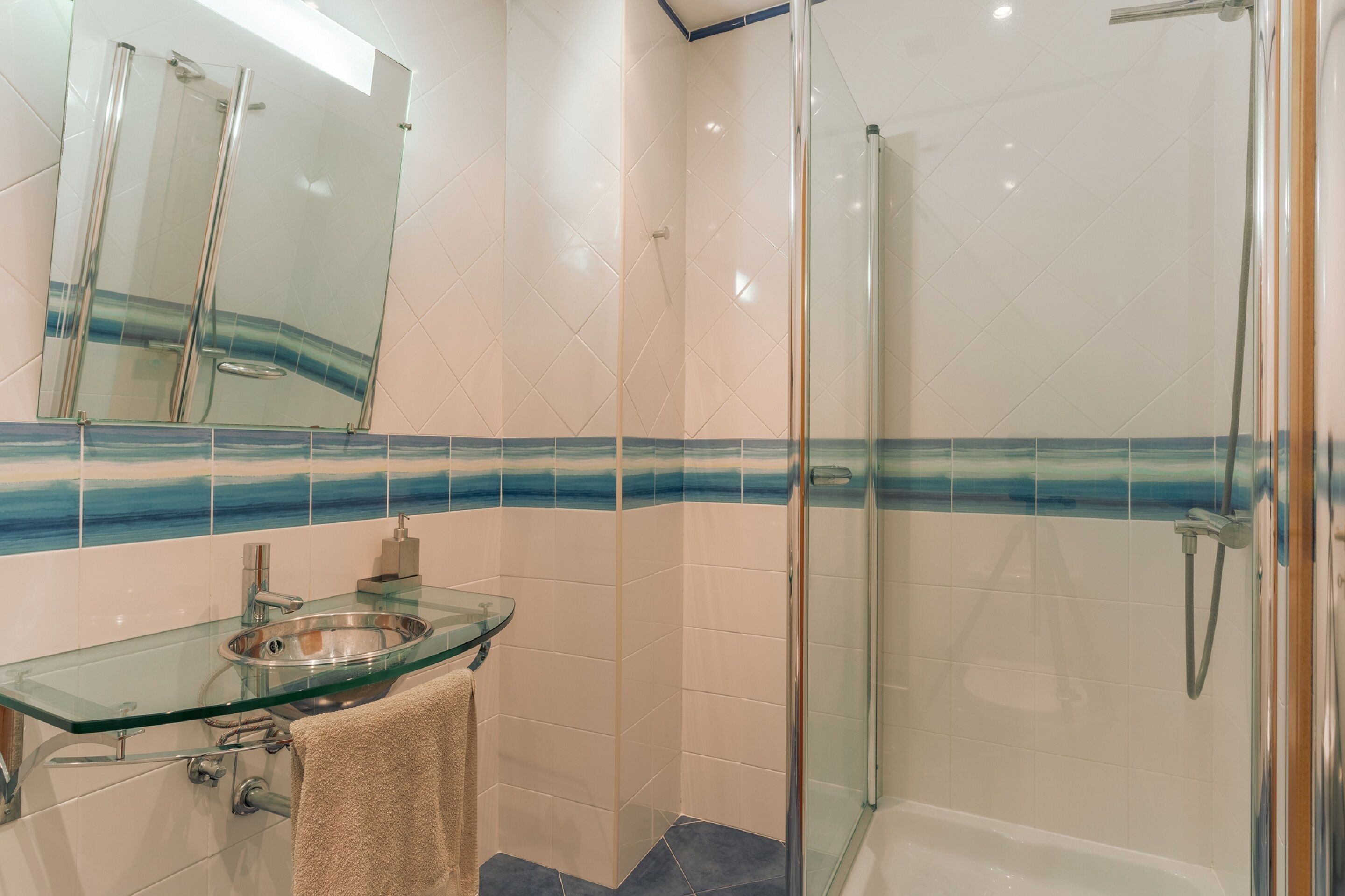 A bathroom with a glass sink, a bathtub, and a glass-enclosed shower.