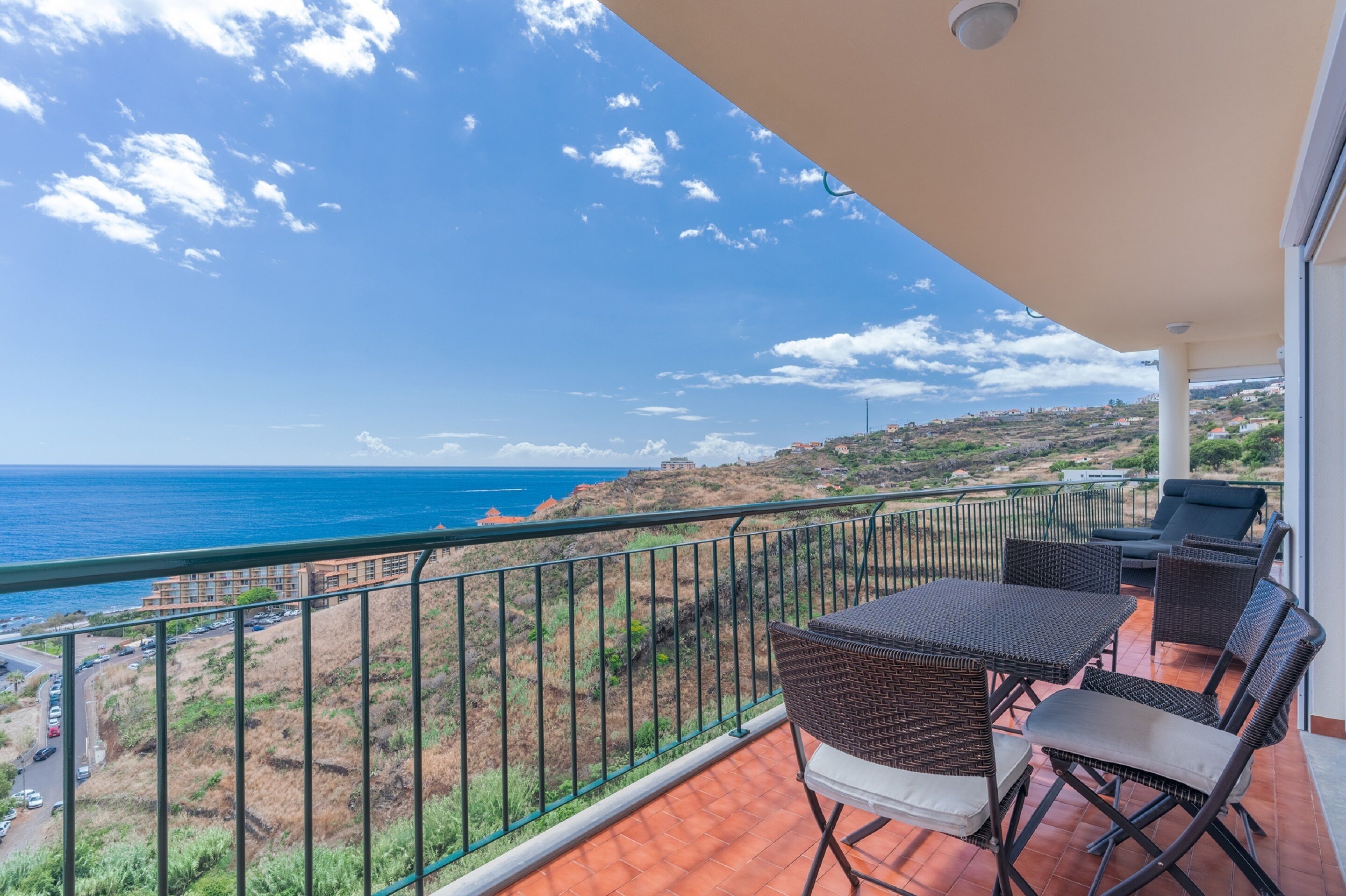 A balcony with outdoor furniture overlooking a coastal view.