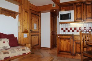 Ambiente interno in legno con angolo cottura, dotato di mobili, forno a microonde e zoccolo di piastrelle.