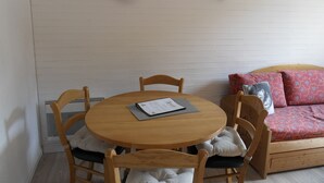 Une pièce chaleureuse avec une table ronde en bois, quatre chaises en bois, un canapé agrémenté de coussins à motifs et une tête de cerf fixée au mur.