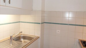 Une cuisine avec des carreaux blancs, un évier en acier inoxydable et des armoires en bois.