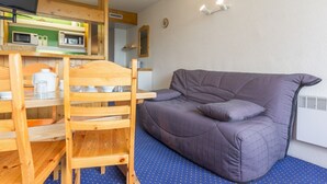 Een kamer met een houten eettafel, een paarse bank en een magnetron aan de muur.