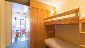 A bunk bed room with wooden walls and a desk area visible through an open door. - travelski home classic - Résidence Grand Arbois - Studio 4 personnes n°621 (Les Arcs)