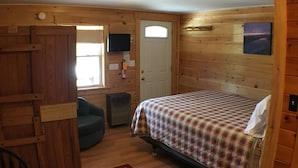 A cozy room with a bed, a television, and a wooden door. - Mountain View Motel & Campground (Stratton)