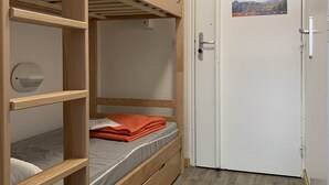 Habitación con literas, puerta y un tablón de anuncios.