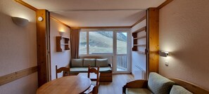 A cozy room with a wooden table, a cushioned bench, and a sofa. - travelski home classic - Vue Pistes - Studio 3/4 personnes L19 (La Plagne)