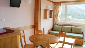 Una habitación acogedora con una mesa y sillas de madera, estantería empotrada, televisión y ventana con vistas al exterior.