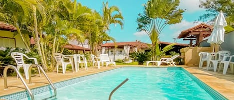 Una piscina al aire libre, sillones reclinables de piscina